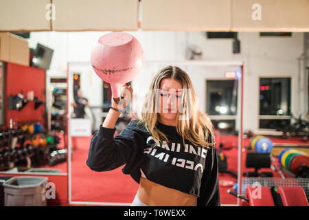 Fit woman exercising with pink kettlebell in the gym Stock Photo