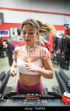 Attractive young woman running on treadmill at the gym. Stock Photo