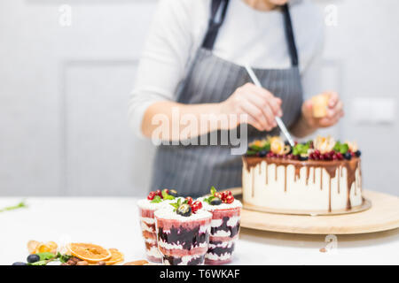 Decoration of the finished dessert. Pastry chef sprinkles confectionery with yellow powder. The concept of homemade pastry, cooking cakes. Stock Photo