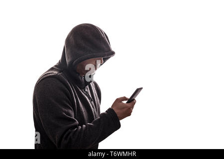 Hooded hacker holding smartphone isolated on white background Stock Photo