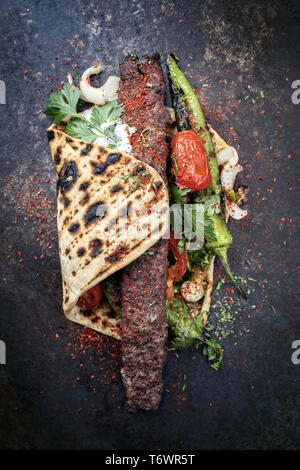 Traditional Adana kebap with tomato and yogurt on a flatbread Stock Photo