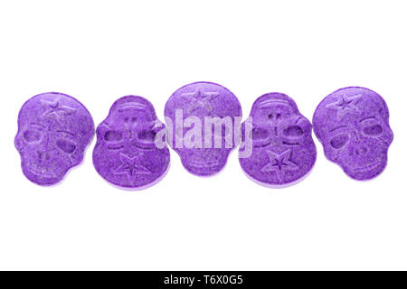 Five purple army Skull, Ecstasy, MDMA, Amphetamine or medication pills shaped like a skull isolated on a white background. Stock Photo