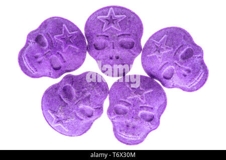 Five purple army Skull, Ecstasy, MDMA, Amphetamine or medication pills shaped like a skull isolated on a white background. Stock Photo