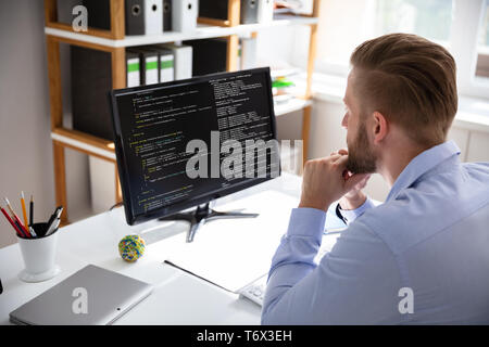 Computer programmer writing program code on computer in office Stock Photo