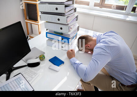 Stressed Businessman Looking Down Near Folders While Working At Desk Stock Photo