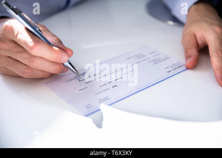 Close-up Of Human Hand Writing On Cheque Stock Photo