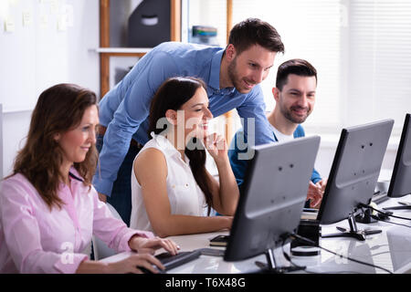 Group Of Happy Business People Using Laptop Discussing At Workplace In Office Stock Photo