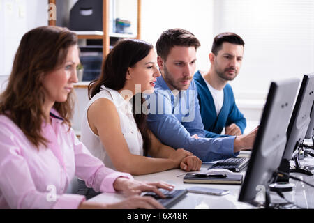 Businessman Pointing On Computer Screen While Talking With Her Colleague Stock Photo