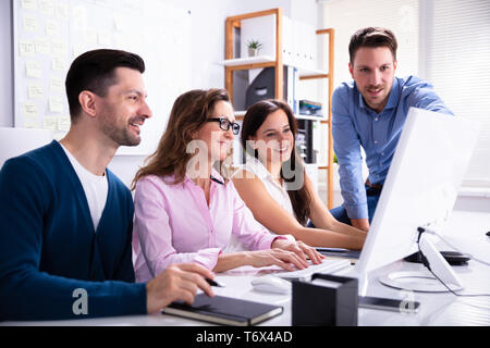 Young Businessman Explaining Plan To Colleagues On Compute At Workplace Stock Photo