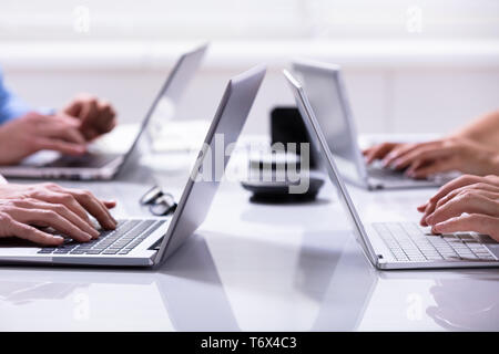 Close-up Of A Businessman Hands On Laptops Keypads On Desk In Office Stock Photo