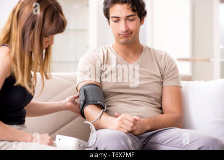 Wife checking husband's blood pressure Stock Photo