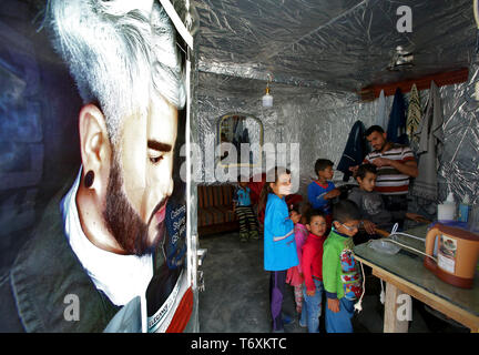 Anjar, Lebanon. 03rd May, 2019. A Syrian refugee barber cuts the hair of a boy at his make-shift barber tent at a refugee camp. Credit: Marwan Naamani/dpa/Alamy Live News Stock Photo