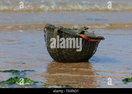An olive-green M1 combat helmet of the US Army at Omaha Beach in Normandy, France Stock Photo