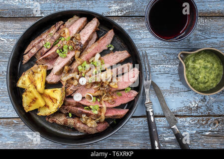 Barbecue dry aged wagyu flank steak with pineapples and chimichurri sauce as top view on a plate Stock Photo