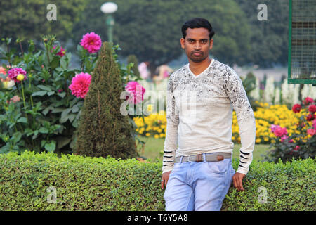 young man model standing in a garden with flower background Stock Photo