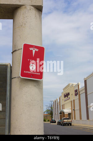 In May 2019, it was announced that Tesla, Inc. co-founder/CEO Elon Musk was one of the winners of the 2019 Stephen Hawking Medal for Science Communication. Pictured in April 2019, in vertical orientation and with various stores in the background at the Towne Centre at Laurel shopping center/centre in Laurel, Maryland, USA, a red 'Tesla Supercharger' sign with logo on a pillar of the parking garage/multi-storey car park where charging stations are available for the California-based automotive company's electric vehicles. As of May 2019, Tesla had more than 1,440 Supercharger stations worldwide. Stock Photo