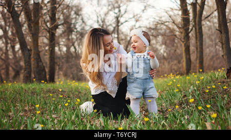 Toddler gives mom a forest tulip. Young attractive woman sniff the scent of a flower presented by a cute daughter for mother's day. They walk in the s Stock Photo