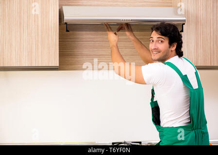 Young contractor repairing air-conditioner in kitchen Stock Photo