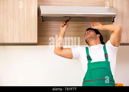 Young contractor repairing air-conditioner in kitchen Stock Photo