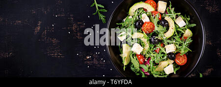 Green salad with sliced avocado, cherry tomatoes, black olives and cheese. Healthy diet vegetarian summer vegetable salad. Table setting. Food concept Stock Photo