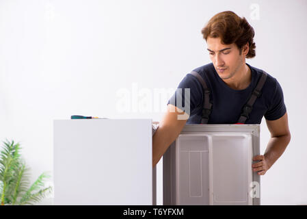 Young handsome contractor repairing fridge Stock Photo
