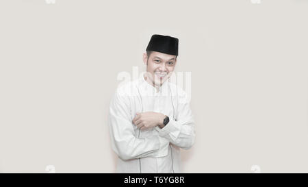 Portrait of cheerful young Asian muslim man smiling in front of camera using peci or head cap -image Stock Photo