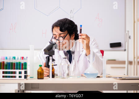 Young funny chemist in front of white board Stock Photo