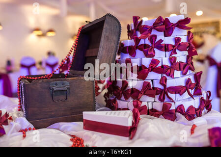 wooden chest on the table with a violet tablecloth and small gifts for guests from the newlyweds Stock Photo