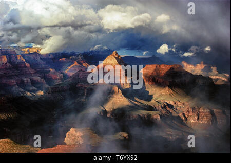 The Grand Canyon in Arizona, is illuminated by late afternoon light shining through cloudy skies during a brief clearing in an early winter storm. Stock Photo