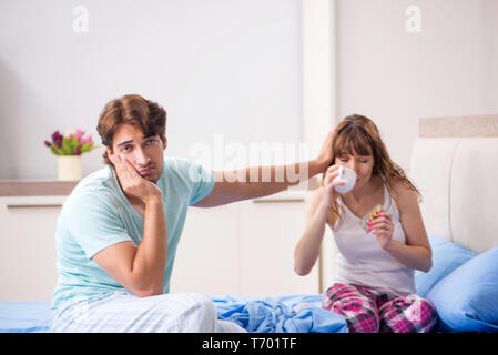 Young husband looking after sick wife in the bedroom Stock Photo