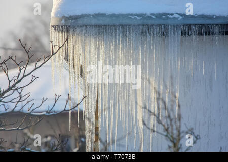 Roof with icicles hanging from roof. Stock Photo