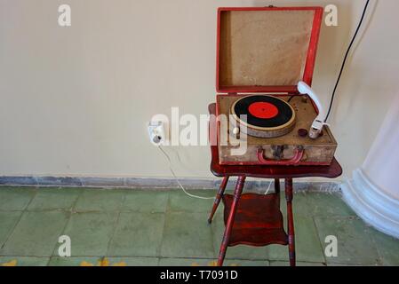 Weathered Vintage Old Phonograph on a Wooden Stool in an empty room against white wall background Stock Photo