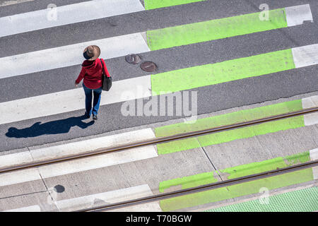 Elegant slender woman in a hat, red cardigan and jeans crosses the road on a zebra pedestrian crossing observing the rules of the road to protect your Stock Photo