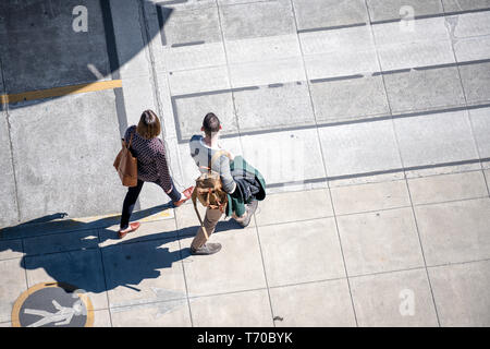 Couple a man with backpack and a woman with bag are confidently walking along the footpath with markings on the sidewalk preferring to move actively t