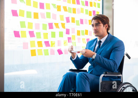 Young handsome man in wheelchair with many conflicting prioritie Stock Photo