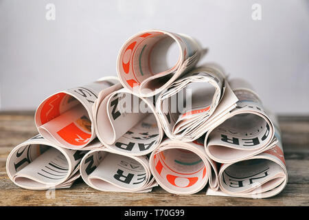 Rolled newspapers on wooden table Stock Photo