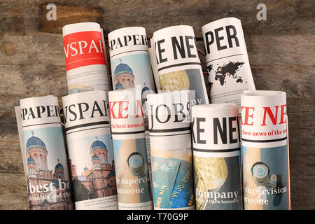 Rolled newspapers on wooden background Stock Photo