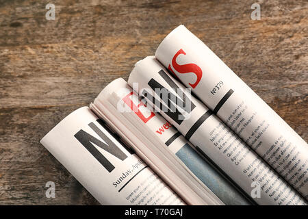 Rolled newspapers on wooden background Stock Photo