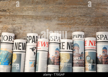 Rolled newspapers on wooden background Stock Photo