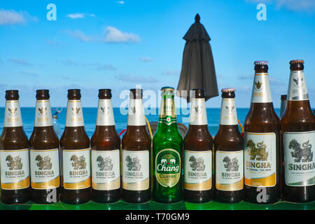 Empty bottles of Singha beer and a lone bottle of Chang beer at a drinks stall at Bang Tao Beach, Phuket, Thailand Stock Photo