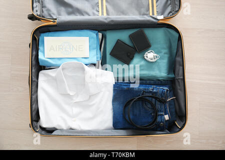 Open suitcase with packed things on floor, top view Stock Photo