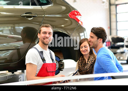 customer service in a garage - mechanic and customer discuss the repair of a vehicle Stock Photo
