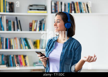 Spanish young adult woman relaxing with music indoors at home Stock Photo