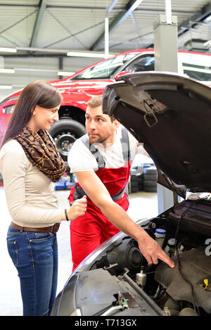 customer service in a garage - mechanic and woman discuss the repair of a vehicle Stock Photo