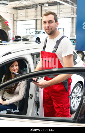 customer service in a garage - mechanic and woman discuss the repair of a vehicle Stock Photo