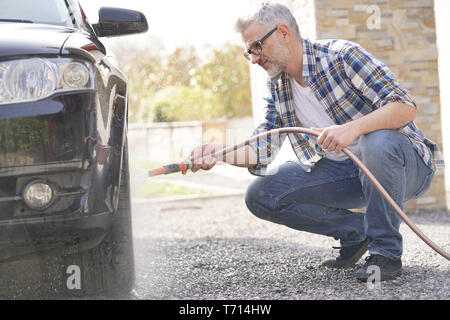 Mature man washing his car in driveway Stock Photo