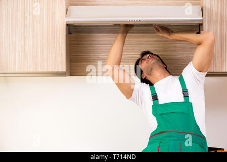 Young contractor repairing air-conditioner in kitchen Stock Photo
