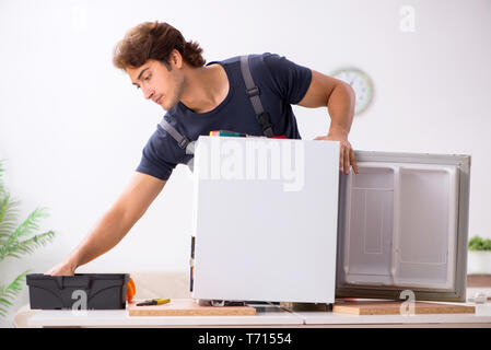 Young handsome contractor repairing fridge Stock Photo