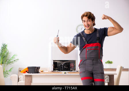 Young handsome contractor repairing fridge Stock Photo