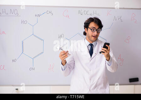 Young funny chemist in front of white board Stock Photo
